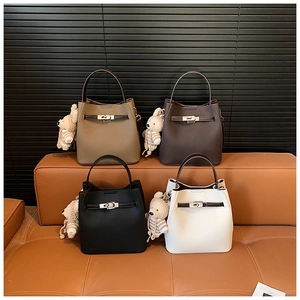 Detail of four retro bucket bags in litchi grain leather with bear charms and metal locks