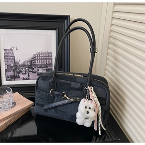 Detail of dark grey plaid tote bag with black leather straps and plush dog charm