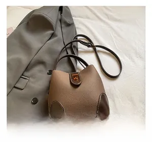 Close-up of brown textured leather bucket bag with metallic lock and strap