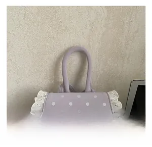 Détail du sac à main violet à pois avec nœud, dentelle et pendentif en cœur