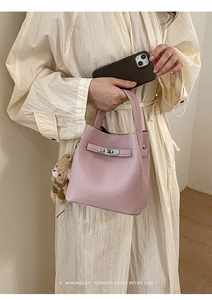 Detail of pink bucket bag with leather texture, metal clasp, and brown plush bear charm