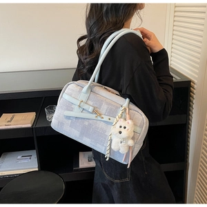 Close-up of light blue denim tote bag with white plush puppy charm and slim handle