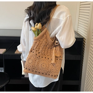 Dettaglio della borsa a spalla intrecciata con perline in legno, nappe e motivi floreali