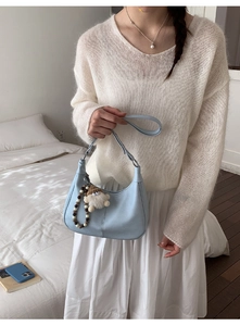 Détail du sac hobo en cuir bleu clair avec charm en peluche et chaîne à perles décorative