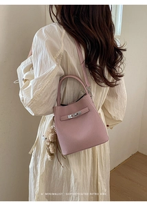 Detail of pink lychee leather bucket bag with top handle and cute plush bear charm