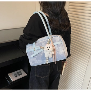 Detail view of light blue checkered canvas tote bag with leather straps and plush puppy charm
