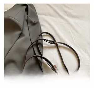 Detail view of brown textured leather bucket bag with adjustable strap and metal lock