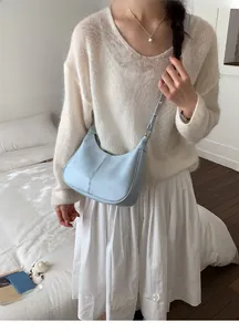 Détail du sac bandoulière croissant bleu clair avec texture fine et boucle en métal