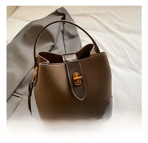 Detail view of dark brown pebbled leather bucket bag featuring a gold metal twist lock