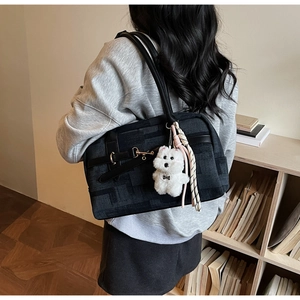 Close-up of black jacquard tote bag with leather strap and cute puppy pendant accessory