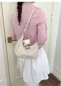 Détail du sac hobo blanc crème en cuir avec un joli pendentif en peluche amovible