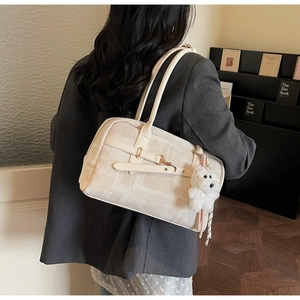 Close-up of textured off-white tote bag with a cute plush puppy charm on the side strap
