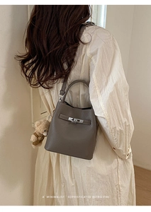 Detail of dark grey lychee leather bucket bag with silver metal turn-lock and teddy charm