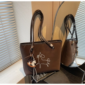 Detail of dark brown tote bag with horse embroidery, unique rope handles and charm