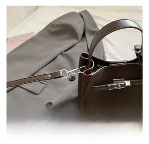 Detail of metal hook connection and lychee pattern leather on dark brown handbag
