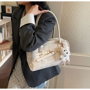 Side view of cream canvas tote bag with puppy charm accessory on a female model