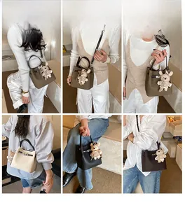 Litchi pattern bucket bag detail with metal clasp and striped teddy bear charm
