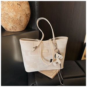 Close-up of beige plaid bucket bag with cartoon horse charm and branded leather patch