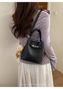 Black pebbled leather bucket bag with silver twist lock and cute bear charm on model