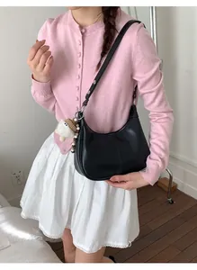 Détail du sac sous le bras en cuir noir avec pendentif peluche et coutures visibles