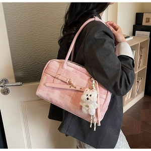 Detailed side view of pink plaid tote bag with plush puppy charm and tassel