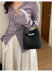 Detail of black lychee grain leather handbag with silver clasp in a minimalist retro vibe