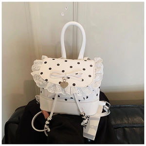 Dettaglio mini zaino bianco con pois, bordo in pizzo e ciondolo a forma di cuore
