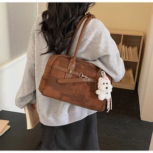 Close-up of brown patchwork PU leather shoulder bag with a white plush dog charm detail