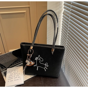 Detail view of black suede tote bag with white line horse art and rocking horse charm