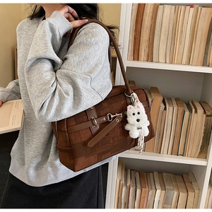 Close-up of brown vintage tote bag with leather trim and a plush puppy charm