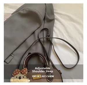 Detail of lychee pattern leather bowling bag with cute plush bear charm and metal plate