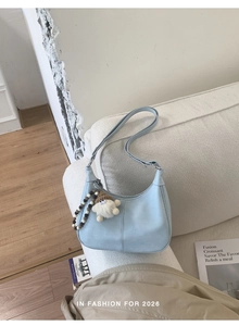 Détail du sac hobo bleu clair avec perles en bois et charm nain sur canapé blanc