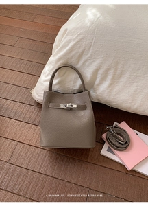 Detailed macro view of taupe lychee leather bucket bag with silver twist lock and strap