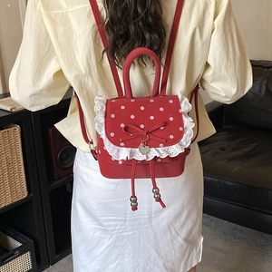 Modella che indossa un mini zaino rosso a pois con pizzo bianco e fiocco sul retro