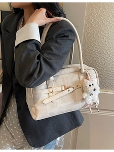 Creamy white checkered tote bag with puppy charm shown on model in grey blazer