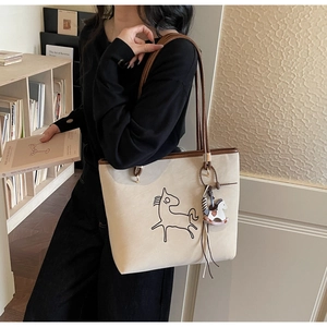 Detail of beige tote bag featuring minimalist horse pattern and long brown shoulder strap