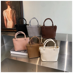 Detailed display of six colorful pleated bucket bags on a metallic display stand