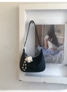 Détail du sac demi-lune noir avec pompon blanc et chaîne décorative perlée