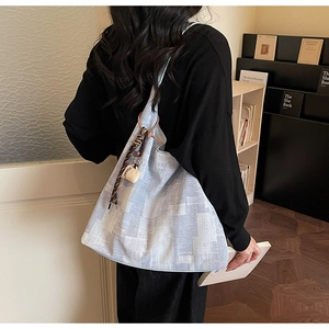 Détail du sac cabas texturé clair avec foulard en soie décoratif et breloque café