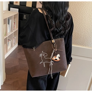 Close-up of a dark brown suede tote bag with horse pattern and leather straps