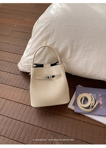 Detailed shot of cream lychee leather bucket bag with metal buckle and shoulder strap