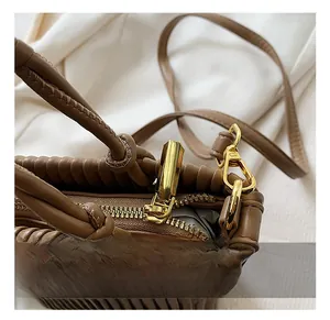 Close-up of golden zipper hardware and pleated dark brown leather on the bucket bag