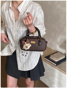 Détail du sac Boston en cuir marron foncé avec charm ours et fermeture éclair dorée