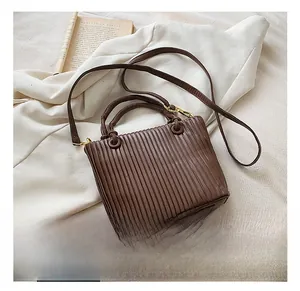 Detail view of the brown bucket bag with accordion pleats and gold-tone hardware