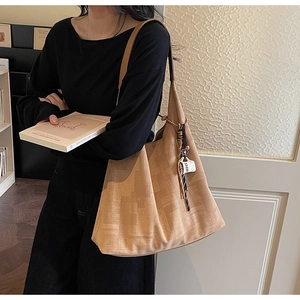 Detail of khaki textured tote bag featuring a leather strap and coffee cup charm