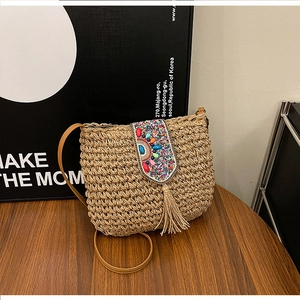 Detail of handcrafted straw bag with colorful beads and long fringe on a wooden table