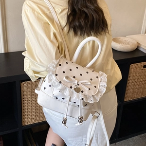 Zaino bianco a pois con pizzo e fiocco mostrato in un ambiente domestico minimalista