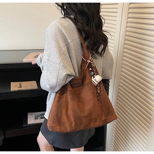 Détail d'un sac cabas marron foncé texturé avec charm café et pendentif tressé