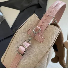 Detail of metal buckle and textured pink leather on a bucket bag with bear charm