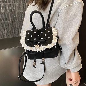 Dettaglio di un mini zaino nero a pois con bordi in pizzo e un ciondolo a cuore